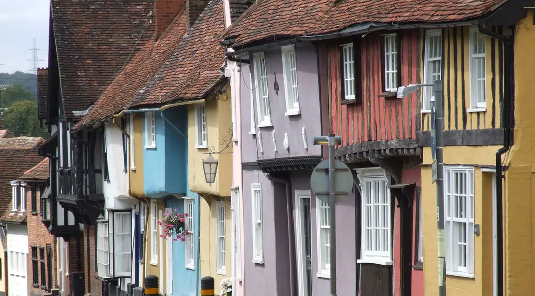 A row of timber-framed houses painted blue, cream, lilac, red and yellow on Castle Street in Saffron Walden.