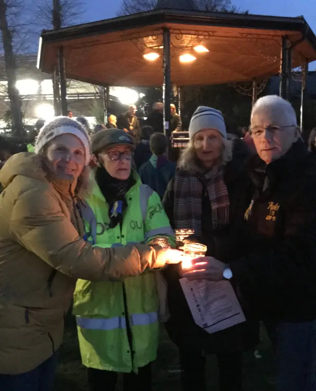 People holding candles at a vigil at dusk.